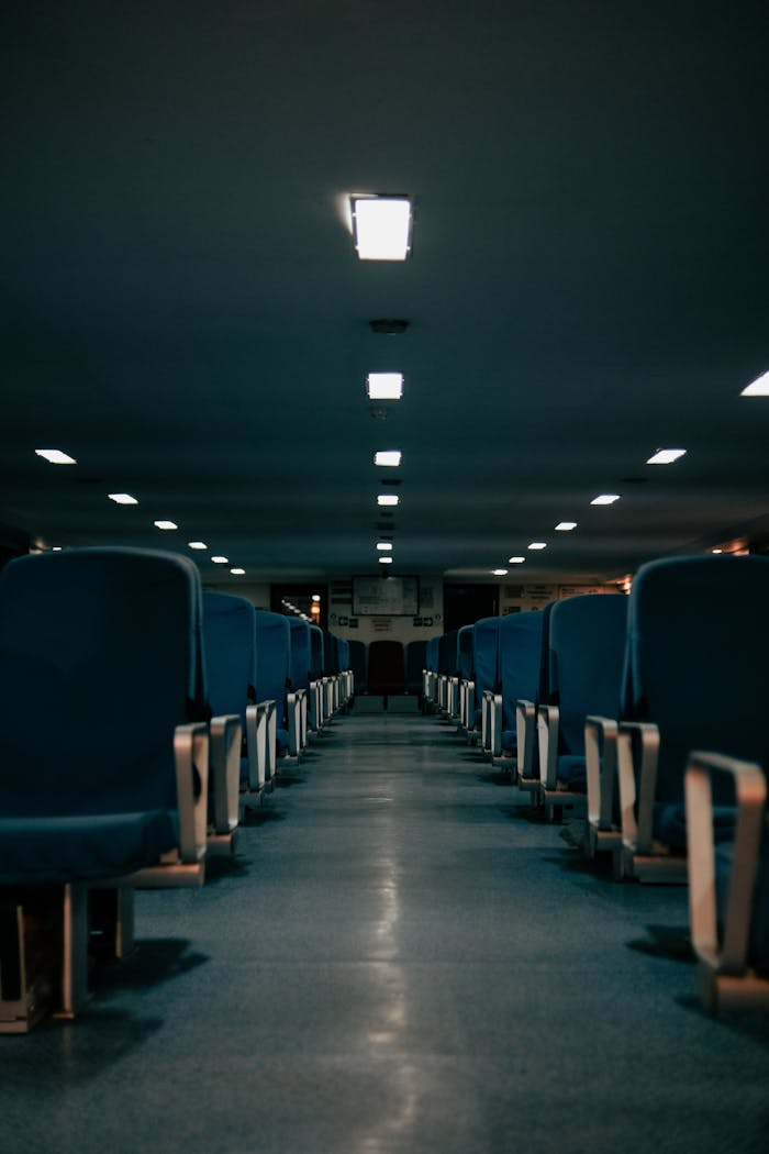 brand-01 Dark, empty auditorium with rows of blue seats and overhead lighting.