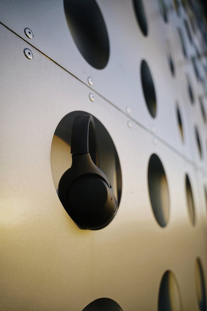 creative-03 Black wireless headphones on a perforated metal surface, showcasing modern design.