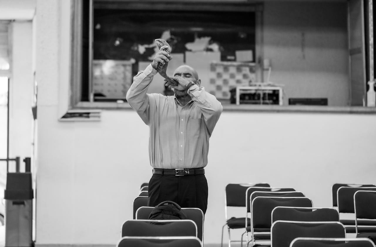 creative-01 A bald man stands playing the shofar in an empty hall in Ciudad de México.