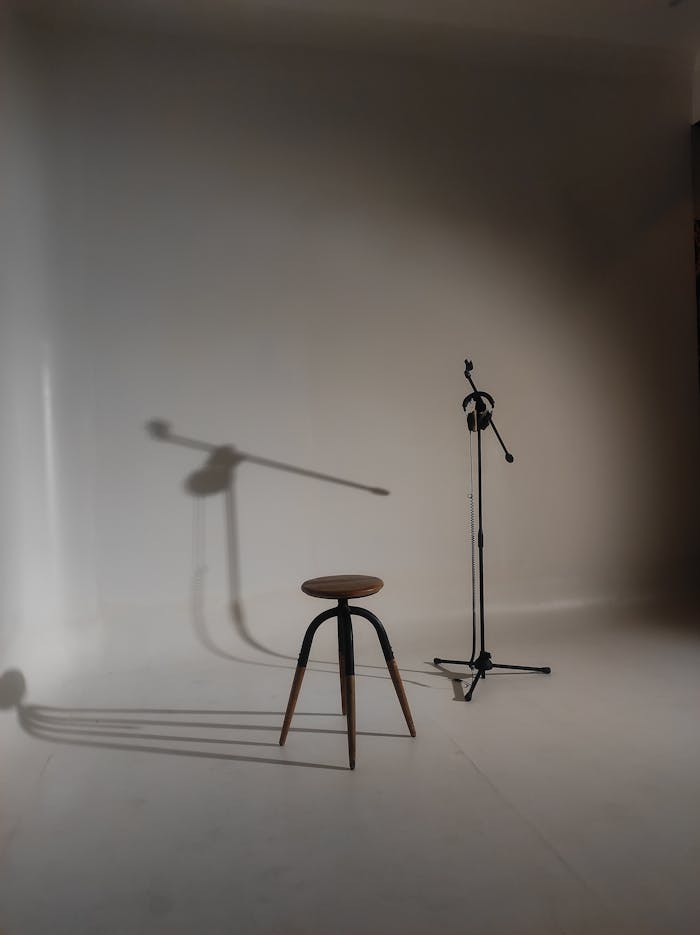 digital-01 A minimalist studio setup featuring a stool and microphone stand casting shadows.