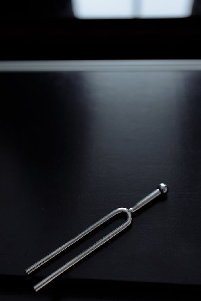 creative-02 Close-up of a tuning fork on a sleek black surface with copy space.