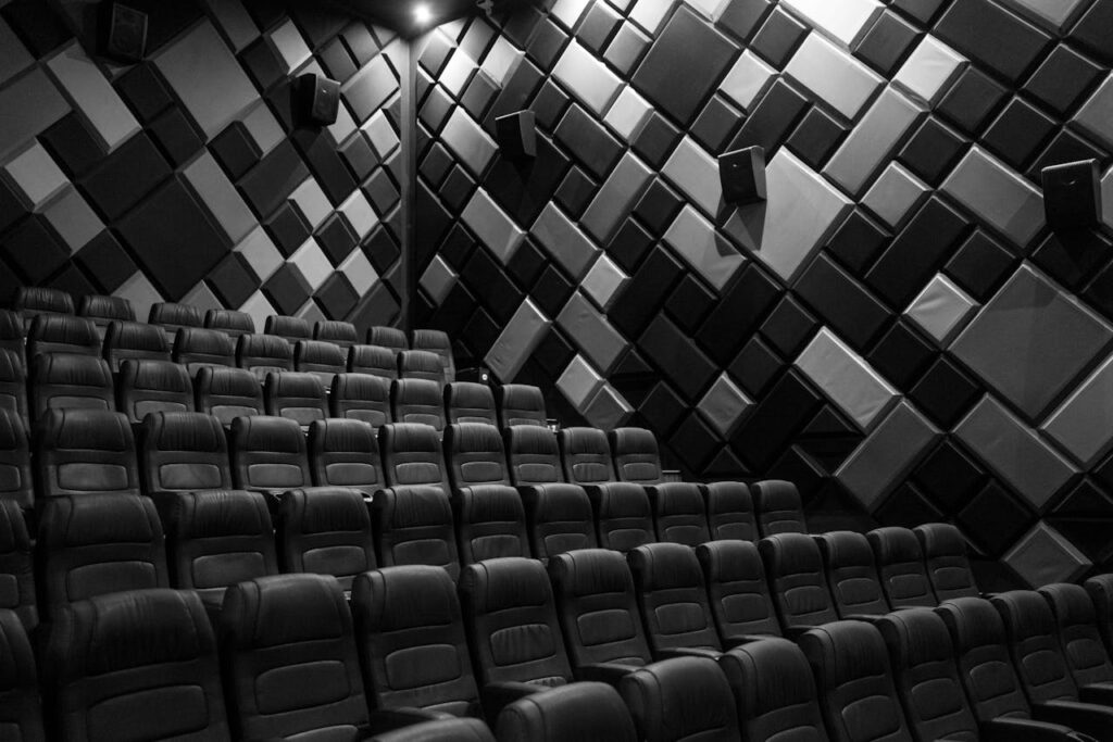 pexels-photo-7234214-1 Interior of an empty cinema hall with leather seats and acoustic walls in grayscale.